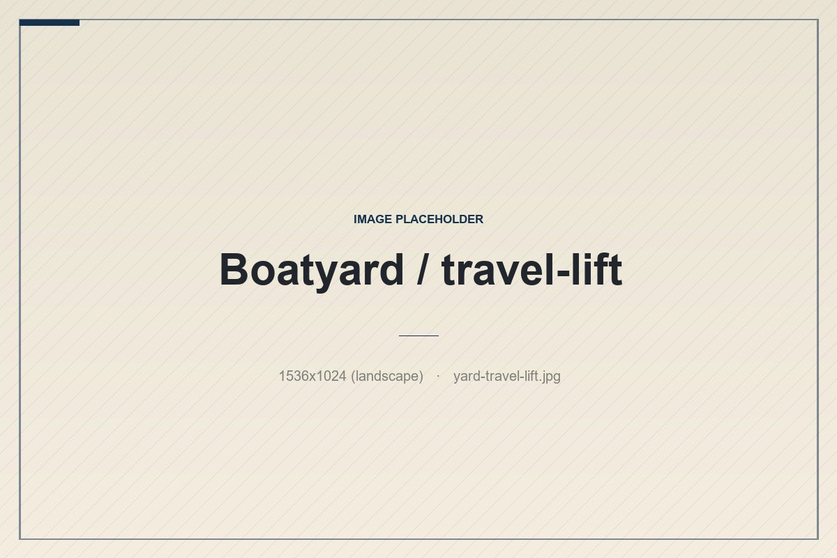 Blue travel-lift hoisting a sailboat hull at a Maine boatyard